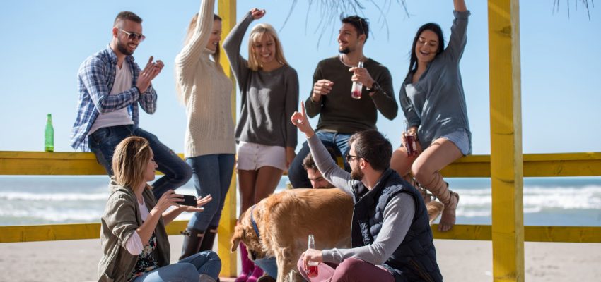 Group of friends having fun on autumn day at beach